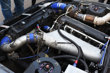 Fototapeta premium Sports car engine with turbine. An open race car hood on a pit stop while racing on a race track. Motor with turbocharger. Boos and tunning.