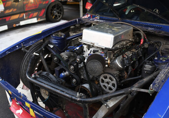 Plakat Sports car engine with turbine. An open race car hood on a pit stop while racing on a race track. Motor with turbocharger. Boos and tunning.