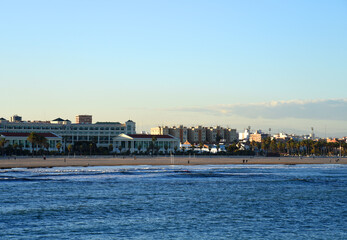 Fototapeta premium View on coastline and beach from La Marina de Valencia on the sea to the Las Arenas beach, Playa de las Arenas, Platja del Cabanyal and Playa de la Malvarrosa. Waves at sea on sunset.