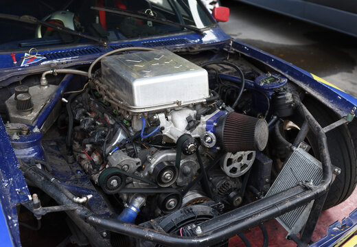 Sports car engine with turbine. An open race car hood on a pit stop while racing on a race track. Motor with turbocharger. Boos and tunning.