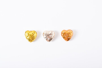 Three shiny hearts in sequins lie on a white background