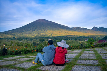 Back view of couple sitting enjoying looking at beautiful scenery of rinjani mountain