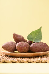 Small purple sweet potatoes from local organic agriculture for sustainability on yellow background.
