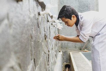 A boy performs ablution before praying at the mosque