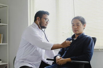 Obraz premium Serious male doctor examining the chest of his anxious patient. Medical procedures