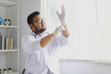 Naklejka na ściany i meble Cheerful male doctor putting on protective gloves