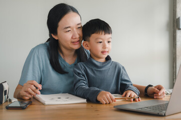 Mother helping little boy taking online courses with a tablet computer. concept of education and technology.