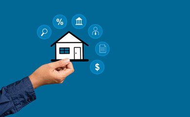 Fototapeta na wymiar Home loan and business real estate concept. Hand holding a mini paper house with business icons while standing on a blue background.