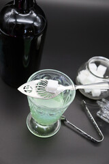 Absinthe in an old scratched vintage glass with sugar cube on absinthe spoon