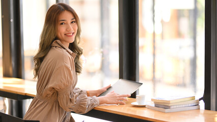 Obraz premium Businesswoman sitting in a co-working space, using tablet.