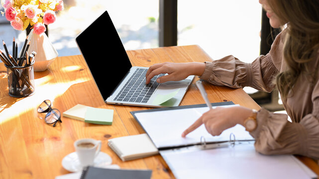 Employee checks and compares the details on a document between laptops.
