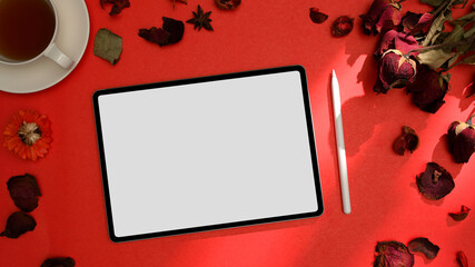 Above view of digital tablet with empty screen, stylus pene on red table