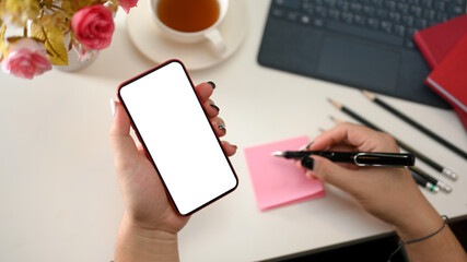 Obraz premium A female hand holding a smartphone blank screen