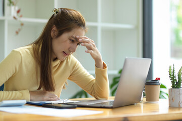 Obraz premium A stressed-out businesswoman sits in front of her laptop screen