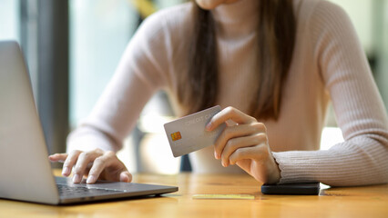 Cropped shot, Woman holding a credit card and using laptop computer.