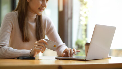 Cropped shot, Woman using laptop computer and holding credit card.