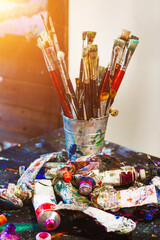 many brushes in a brush holder full of paint from a plastic artist with which he paints his works of art