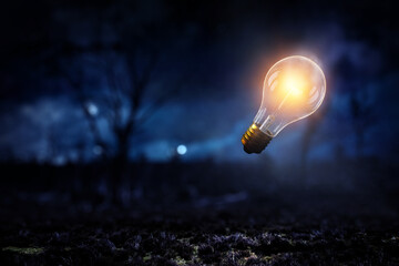 Light bulb glowing in darkness