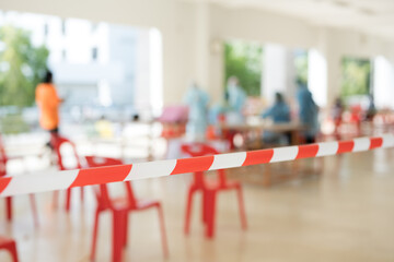 Row of empty red chairs and warning tape infection area.No entry sign concept.Selective focus.