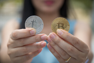 Smiling beautiful Female holding Bitcoin digital currency and cryptocurrency with blur background