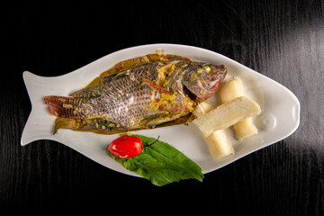 Fish cooked with leaves, peruvian food. Photo above, black background.	