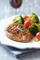 Grilled Turkey Breast with oven baked broccoli, cherry tomatoes and sweet corn. Close up.