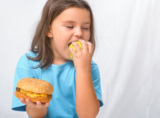 Child girl biting an apple instead of a hamburger