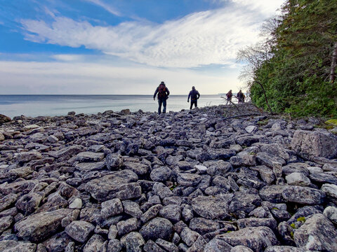 people walking on a rocky beach - Powered by Adobe