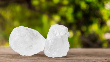 Crystal clear alum cubes or Potassium alum on brown wood plank. Chemical compound substance....