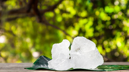 Crystal clear alum cubes or Potassium alum on brown wood plank. Chemical compound substance....