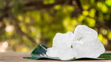 Crystal clear alum cubes or Potassium alum on brown wood plank. Chemical compound substance....