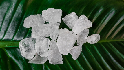 Crystal clear alum cubes or Potassium alum on green leaf. Chemical compound substance. Concept for...