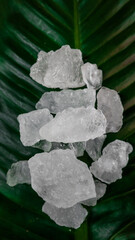 Crystal clear alum cubes or Potassium alum on green leaf. Chemical compound substance. Concept for beauty , spa and underarm treatment industrial. 