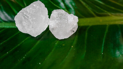 Crystal clear alum cubes or Potassium alum on green leaf. Chemical compound substance. Concept for...