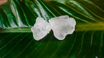 Crystal clear alum cubes or Potassium alum on green leaf. Chemical compound substance. Concept for...