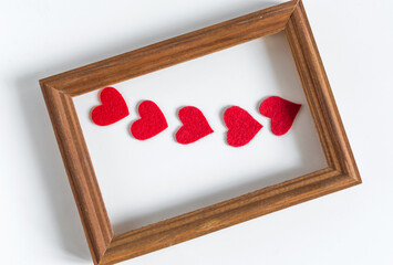 Wooden frame with red hearts, handmade on a light background.