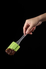 Close up spatula and melted chocolate on black background