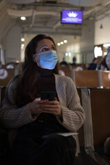 A young woman is sitting in the airport and looking at the table board