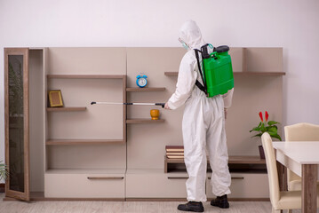 Young male contractor doing pest control at home