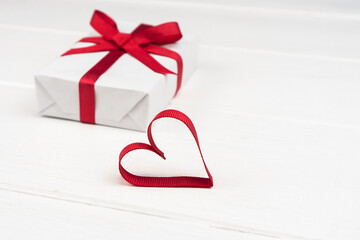 Valentine's Day or birthday concept with copy space. Red ribbon heart and gift box on white wood