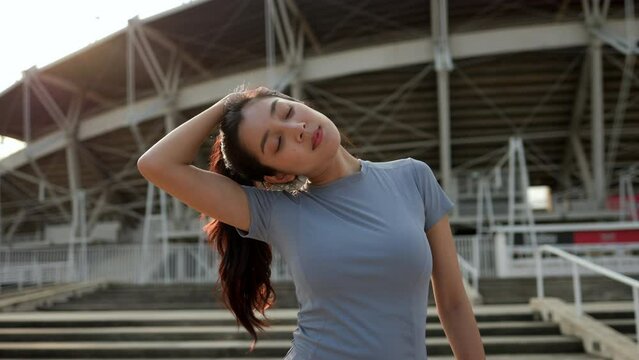 Slim beautiful woman wearing sportswear warming up in the city at sunrise. Confident and powerful woman stretching outdoor. Workout exercise in the morning. Healthy and active lifestyle concept.