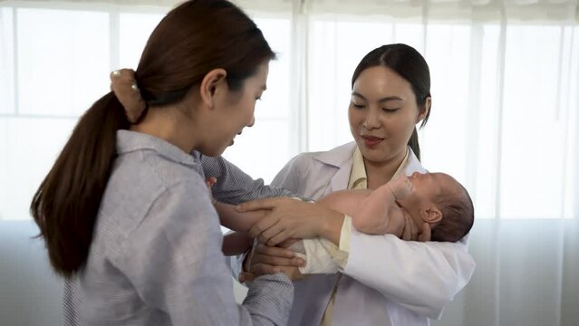 4k, Asian woman holding a newborn baby 2-month-old Asian who is sick for a female doctor Supervise and check the body in the hospital.
