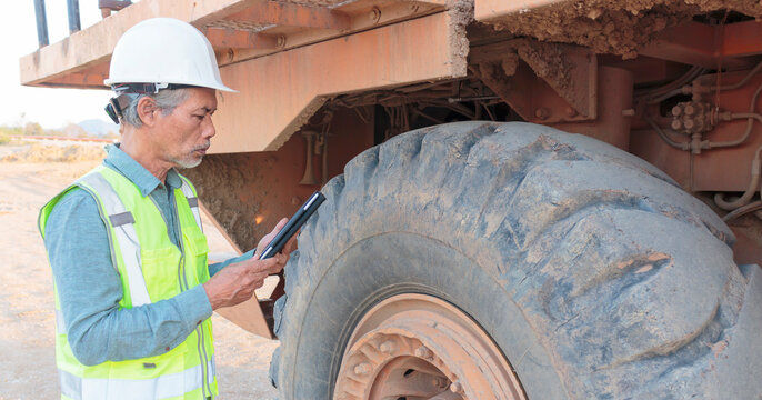 Senior mining engineer uses tablet to inspect the truck