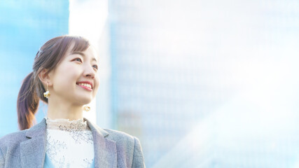 ビル街で空を見上げる若い女性