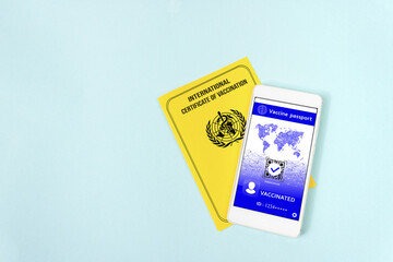 International vaccination record book. Yellow international certificate of vaccination with smartphone displaying valid digital vaccination certificate QR Code for COVID-19. Covid-19 Control.