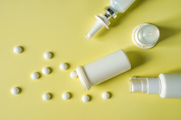 Nasal drops and a spray for the nose or a pill to treat colds and grip. Bottles and vials with medications and colored pills on a green background. Copy space for text