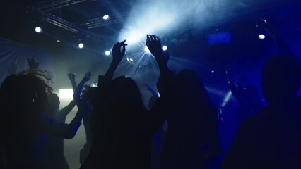 Dancing and jumping in music club. Group of friends enjoying evening. Nightlife, modern music and entertainment concept.