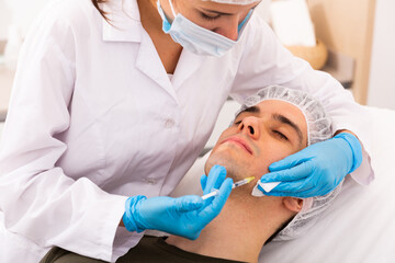 Portrait of male client of aesthetic cosmetology clinic during procedure of face mesotherapy. Male...