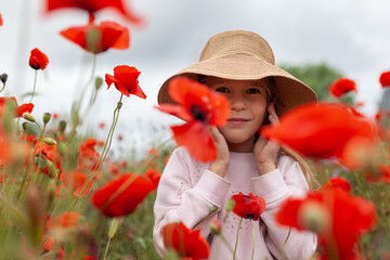 Pretty little girl in a hat on a poppy field