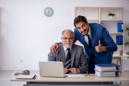 Old male boss and young male employee working in the office